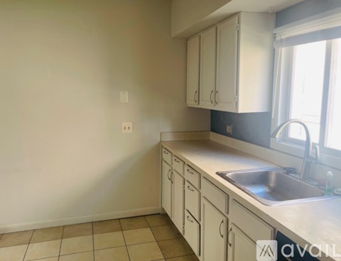 A kitchen with white cabinets and a tiled floor.