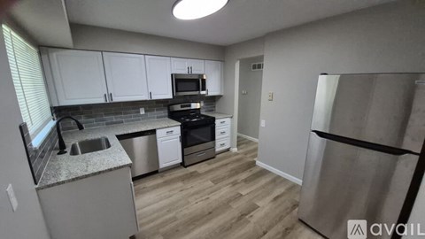 A kitchen with white cabinets and a wooden floor.