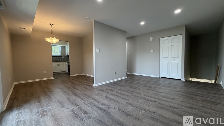 A spacious room with wooden flooring and a chandelier hanging from the ceiling.