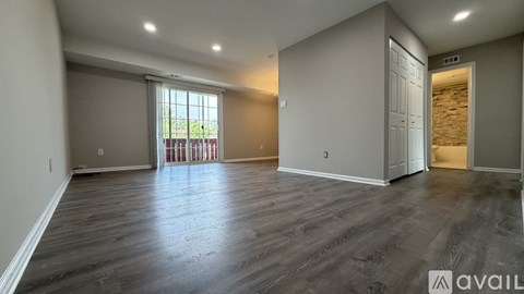A spacious room with wooden flooring and a large window.