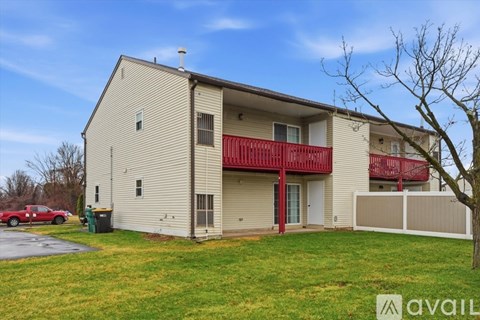 A two-story apartment building with a red car parked in front.