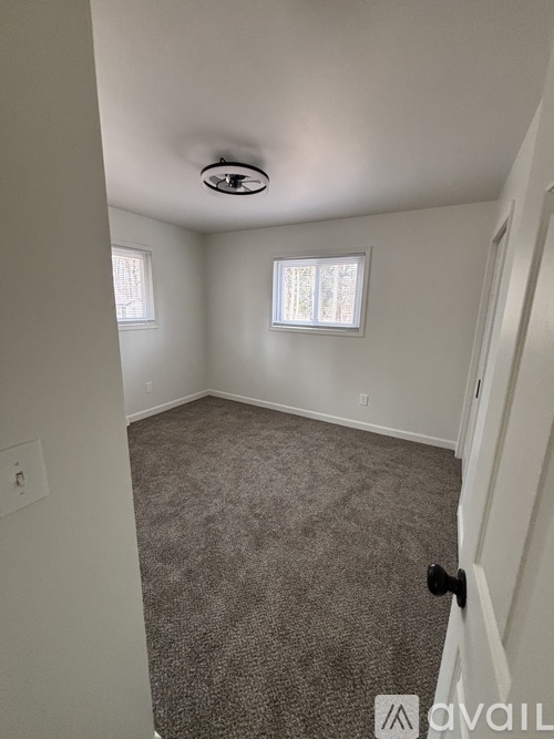 A room with a carpeted floor and a window with blinds.