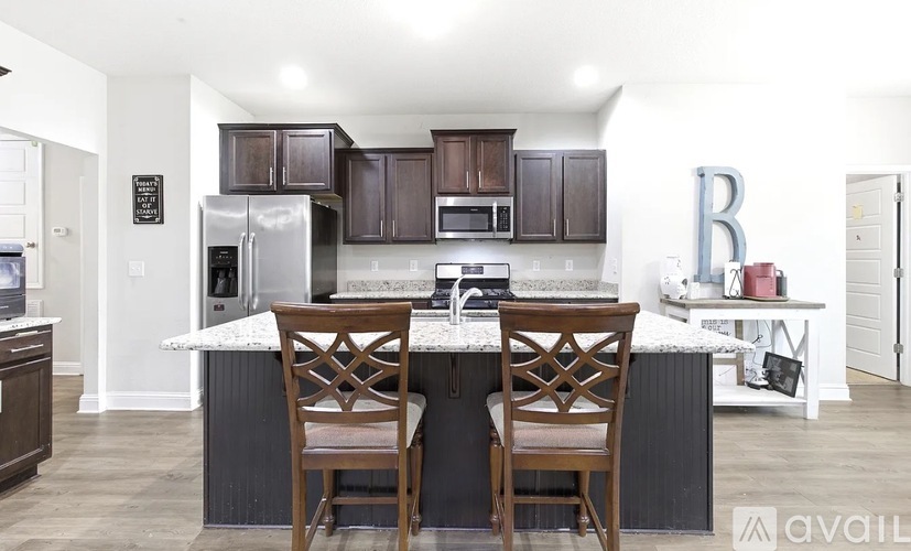 A kitchen with a white island and two chairs.