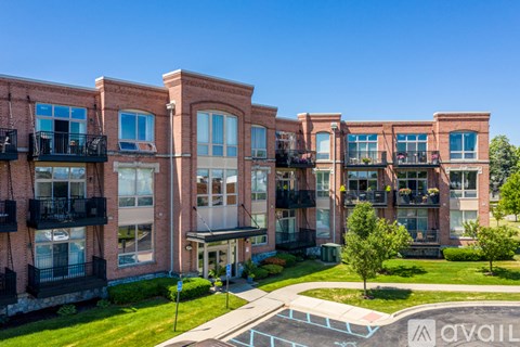 A row of red brick apartment buildings with balconies and green lawns.
