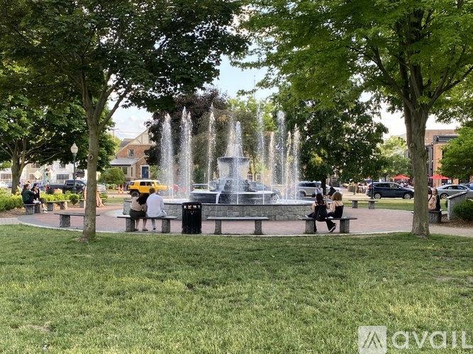 A fountain in the middle of a park with people sitting on benches.