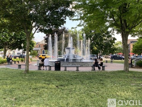 A fountain in the middle of a park with people sitting on benches.