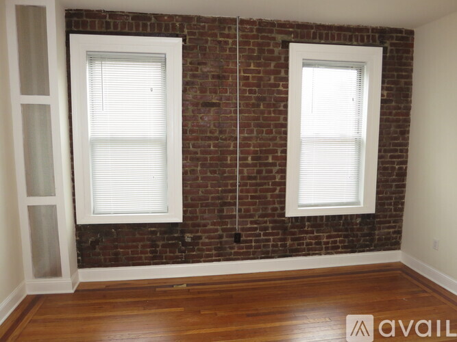 A room with a brick wall and two windows.