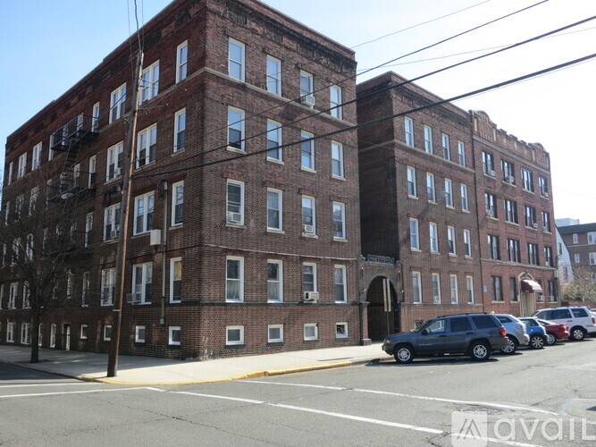 A street view of a red brick building with cars parked in front.