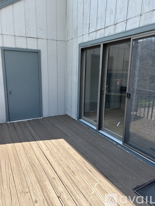 A wooden deck with a grey door and a glass door.