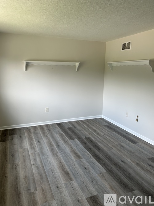 A room with wooden flooring and white walls.