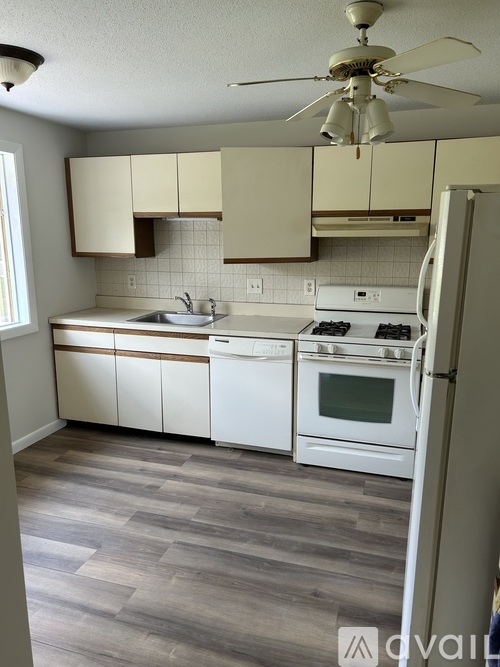 A kitchen with white appliances and wooden cabinets.