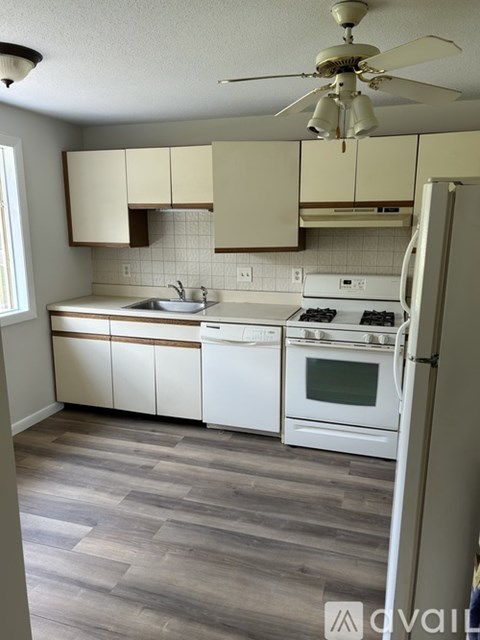 A kitchen with white appliances and wooden cabinets.