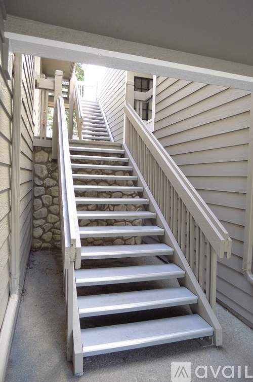 A set of stairs with a stone wall on one side and a wooden railing on the other.
