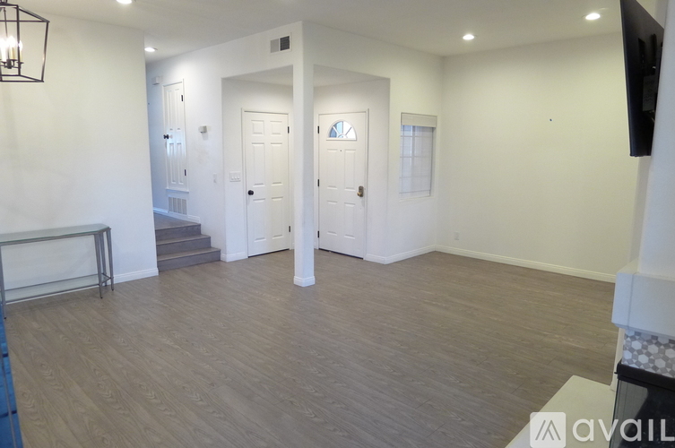 A spacious room with wooden flooring and white walls.