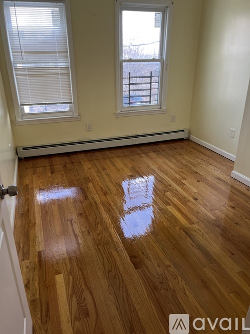 A room with wooden floors and two windows.