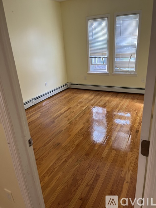 A room with wooden floors and two windows.