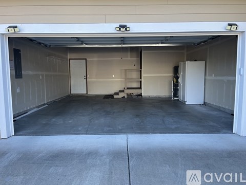 A large, empty garage with a white door and a concrete floor.