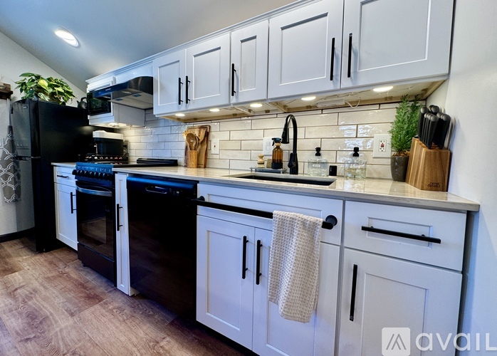A kitchen with white cabinets and black appliances.