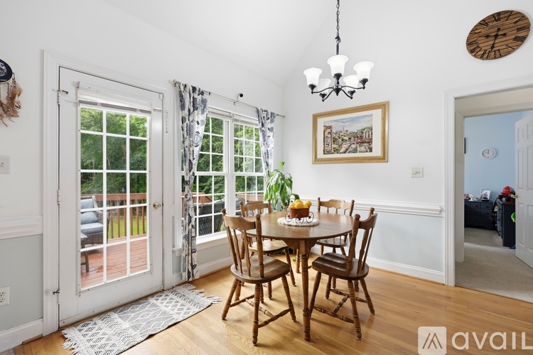 A dining room with a table set for four and a chandelier hanging from the ceiling.
