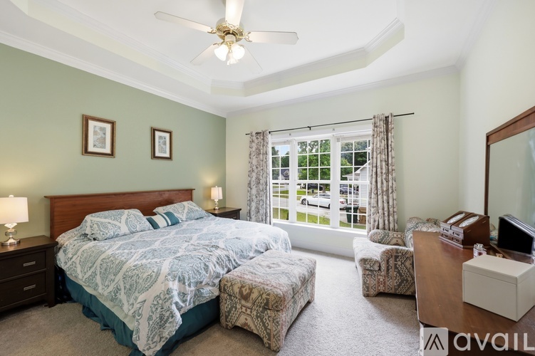 A bedroom with a bed, a chair, a dresser, and a ceiling fan.