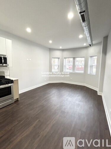 A spacious room with wooden flooring and a stove top oven.