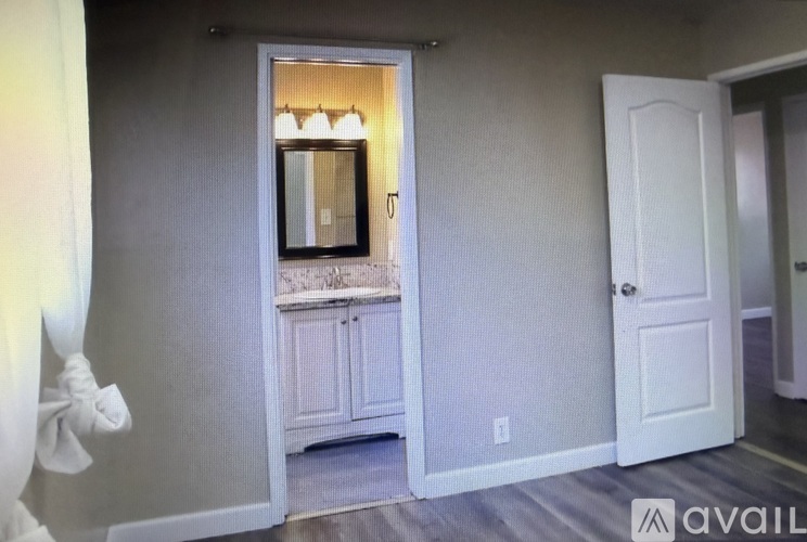 A room with a white door and a cabinet with a mirror above it.