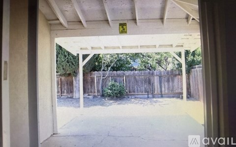 A patio area with a wooden fence and trees in the background.