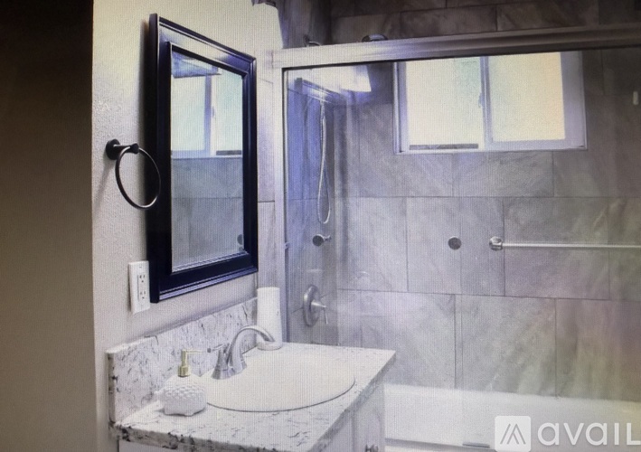 A bathroom with a marble countertop and a large mirror.