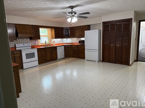 A kitchen with white tile flooring and wooden cabinets.