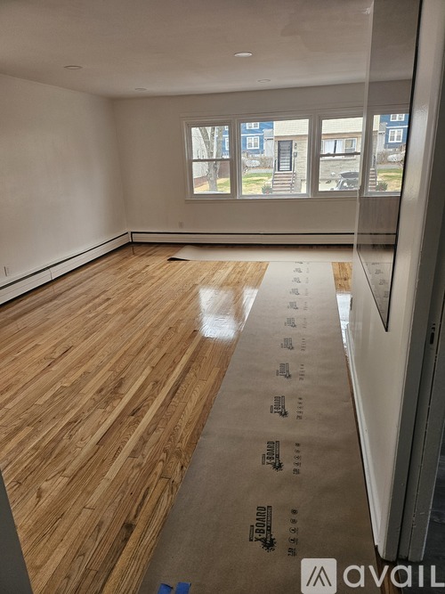 A room with wooden flooring and a window overlooking a street.