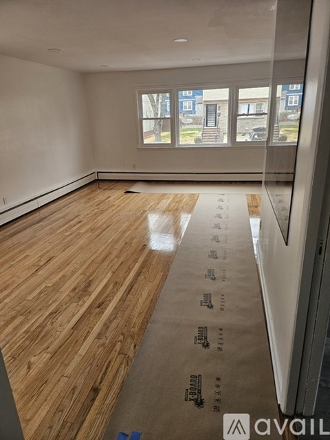 A room with wooden flooring and a window overlooking a street.
