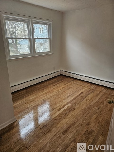 A room with wooden flooring and a window showing a view of a building outside.