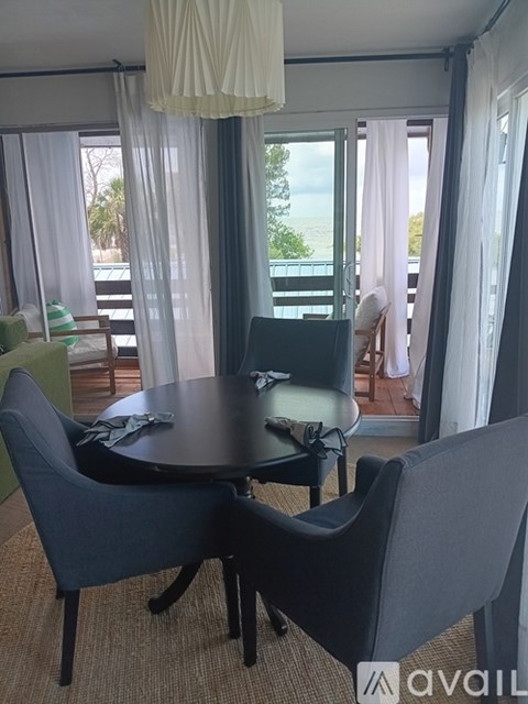 A table with chairs in front of a window with curtains.
