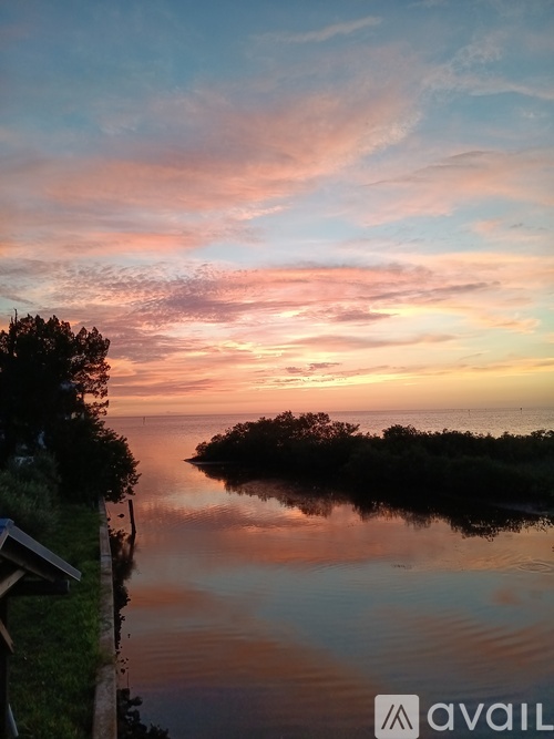 A serene landscape with a body of water reflecting the sky at sunset.