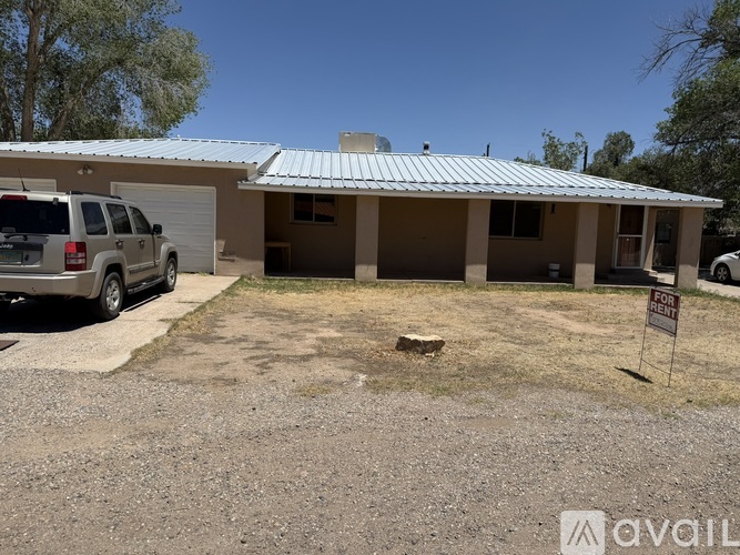 A house with a car parked in front and a for sale sign.