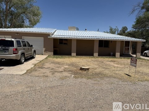 A house with a car parked in front and a for sale sign.