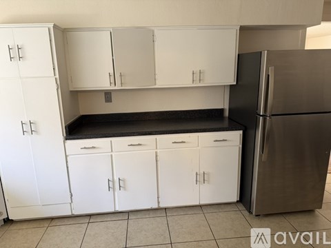 A kitchen with white cabinets and a stainless steel refrigerator.