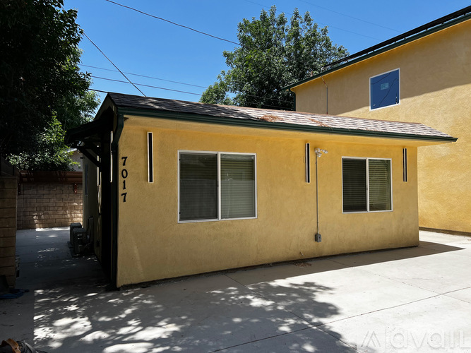 A yellow house with a black roof and a garage door.