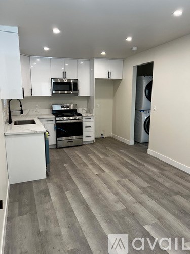 A modern kitchen with white cabinets and a grey floor.