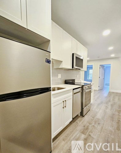 A kitchen with white cabinets and a stainless steel refrigerator.