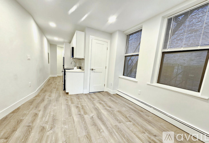 A long, empty room with wood flooring and white walls.