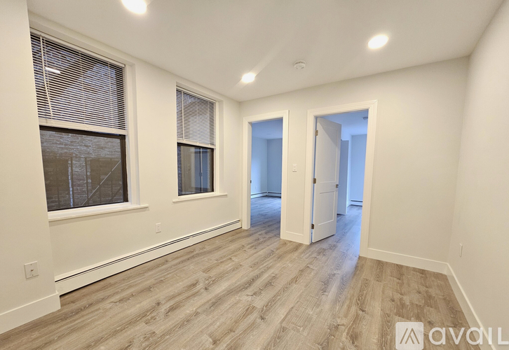 A room with wooden flooring and a doorway leading to another room.