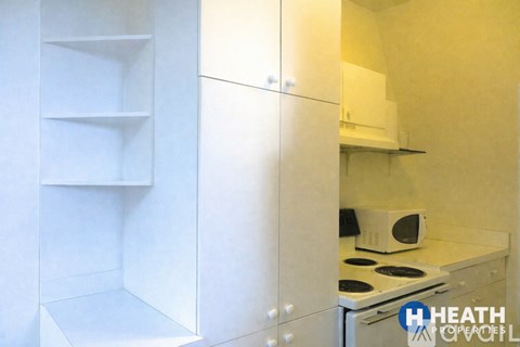 A white kitchen with a microwave on the counter.