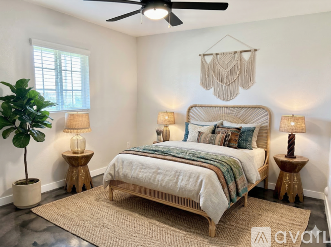 A bedroom with a large bed, a ceiling fan, and a plant.