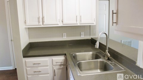 A kitchen with white cabinets and a stainless steel sink.