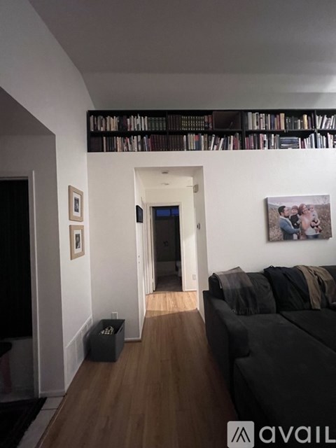 A living room with a black couch and a bookshelf with books.