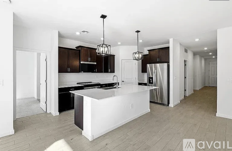 A modern kitchen with a white island and dark brown cabinets.