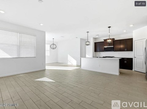 A spacious kitchen with dark brown cabinets and a white island.