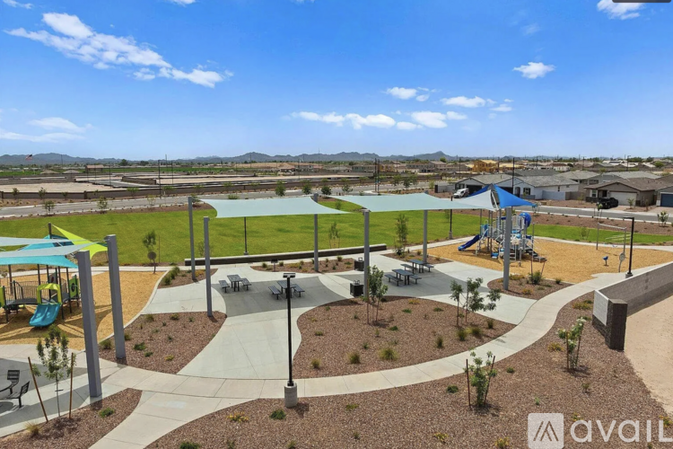 A playground with a blue canopy and a slide is surrounded by a fence.
