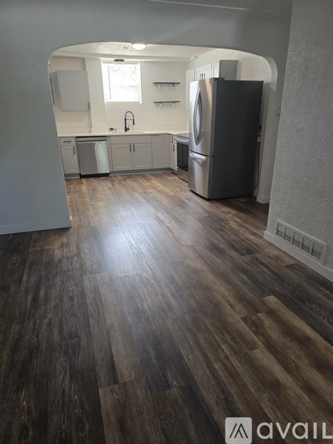 A kitchen with a refrigerator and wooden floors.